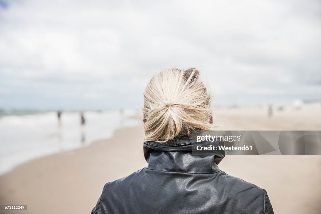 Back view of woman wearing leather jacket on the beach