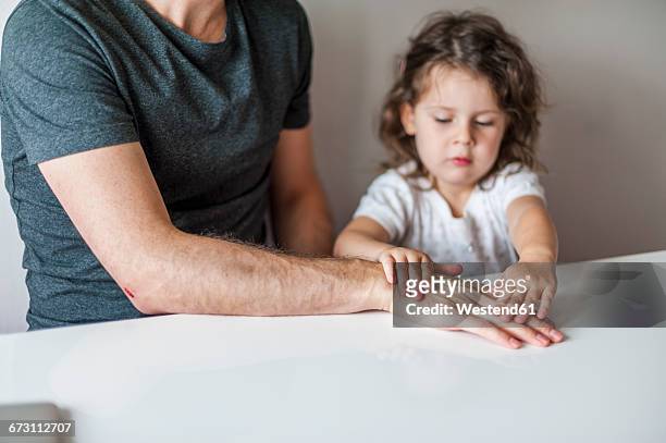 daughter attaching plaster to father's hand - role reversal stock pictures, royalty-free photos & images