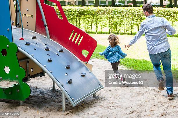 father running with daughter on playground - fangspiel stock-fotos und bilder