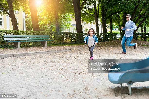 father running with daughter on playground - runaway stock pictures, royalty-free photos & images