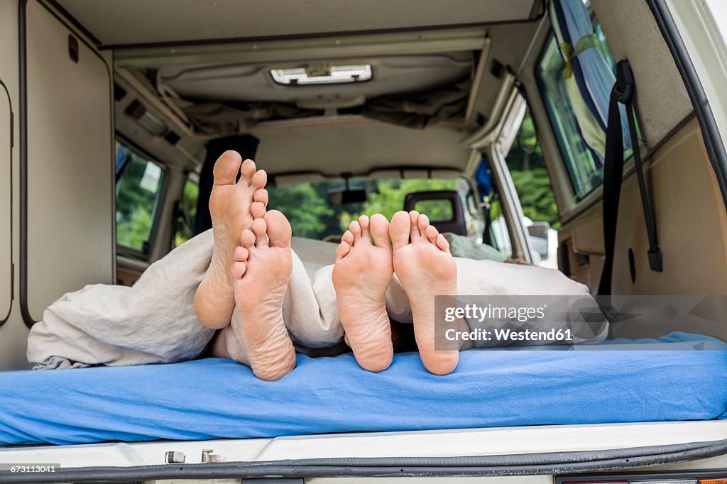 Feet of a couple lying on mattress in van