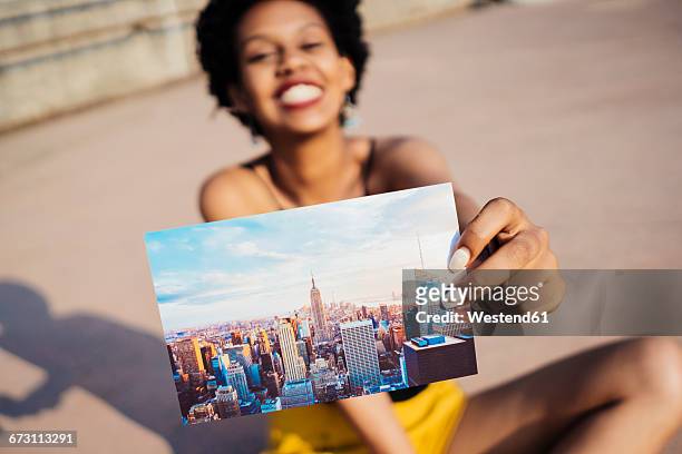 happy woman showing postcard of new york city - ansichtskaart stockfoto's en -beelden