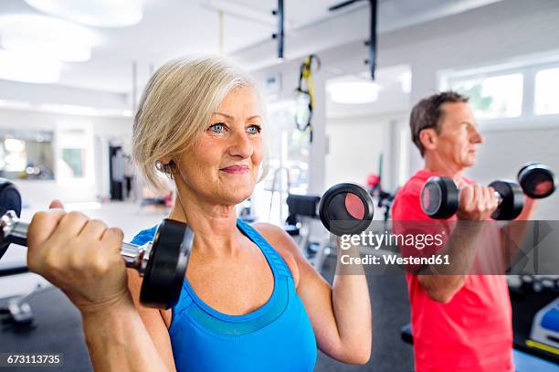 mature woman and senior man working out in fitness gym - krafttraining stock-fotos und bilder