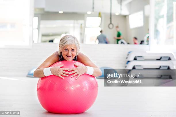 mature woman doing gymnastics on fitness ball in gym - yoga ball stock pictures, royalty-free photos & images