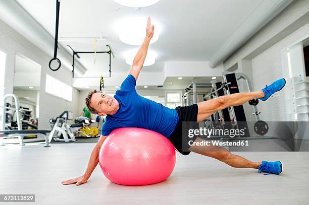 senior man doing gymnastics on fitness ball in gym - fitness ball stock pictures, royalty-free photos & images