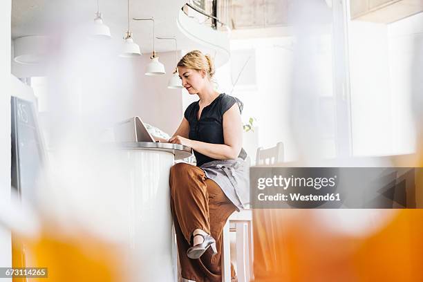 woman using digital tablet in a cafe - fokus auf den hintergrund stock-fotos und bilder