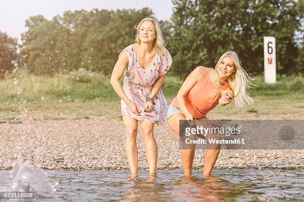 two young women skipping stones in river - skimming stones stock pictures, royalty-free photos & images
