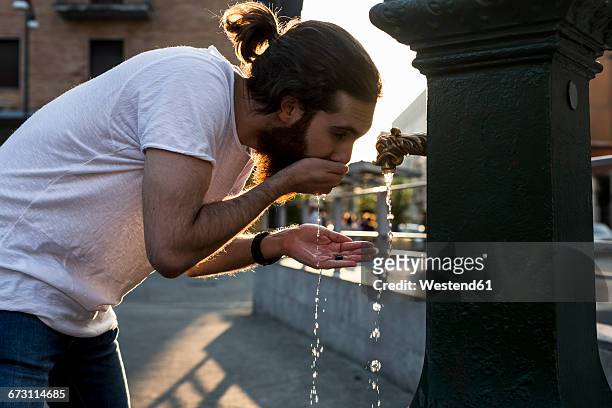 young man drinking water in the city - fountain stock pictures, royalty-free photos & images