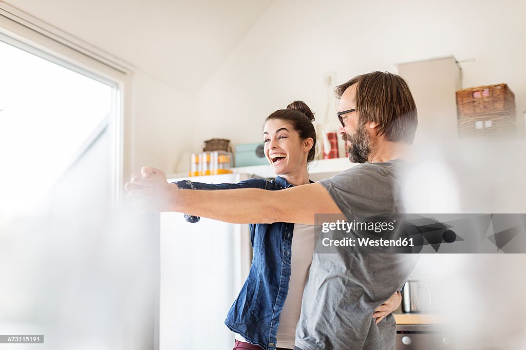 Playful couple dancing in kitchen
