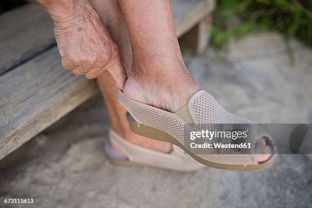 senior woman putting on shoe - old lady feet stockfoto's en -beelden