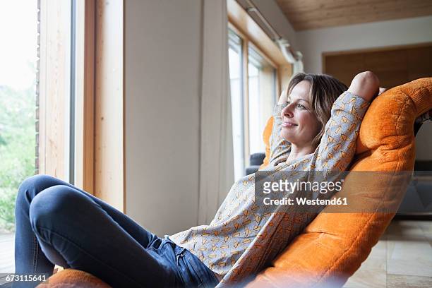 smiling woman relaxing in armchair - hands behind head stock pictures, royalty-free photos & images