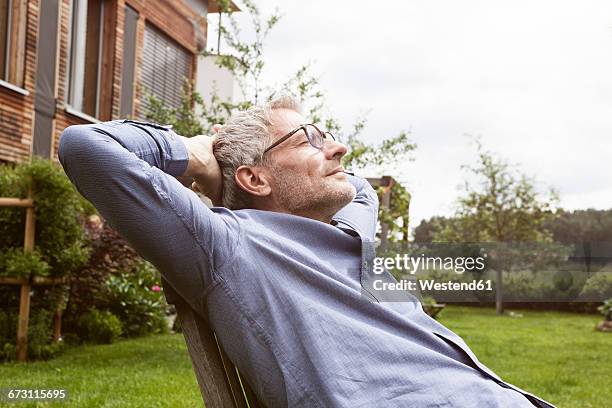 mature man relaxing in garden - wetterfester stuhl stock-fotos und bilder