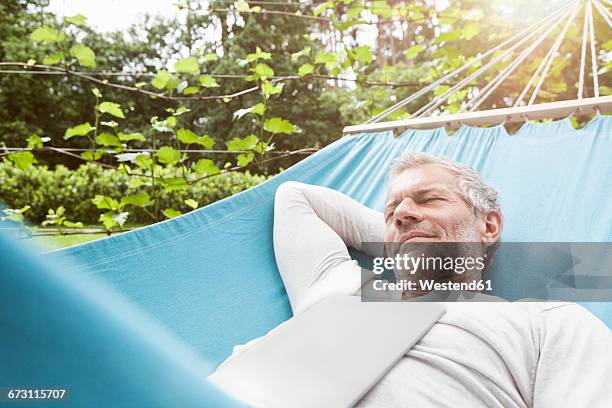 mature man sleeping in hammock with digital tablet on his chest - hammock foto e immagini stock