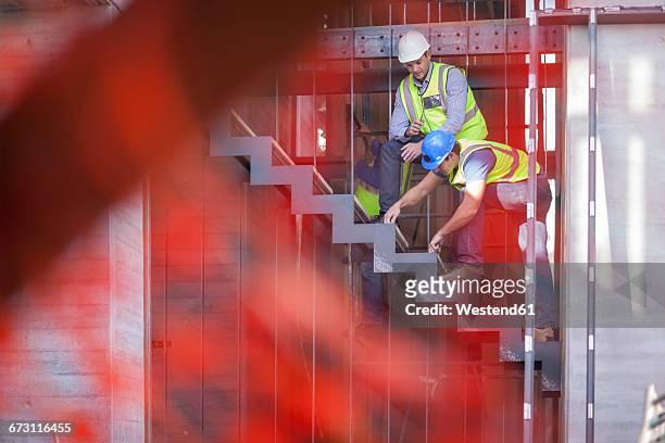 men with reflective vests on construction site - fokus auf den hintergrund stock-fotos und bilder