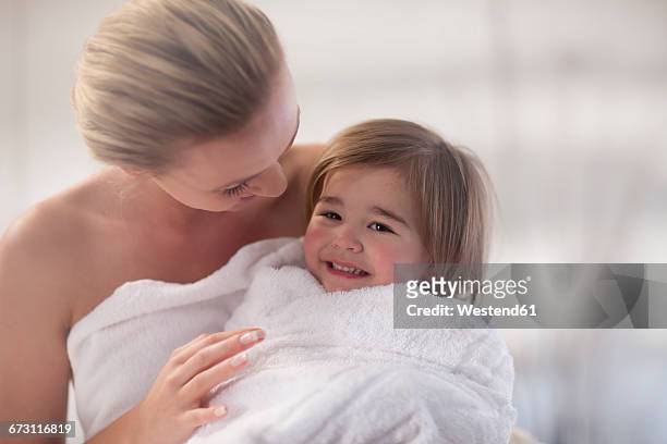 young woman and little girl wrapped in a towel - mother daughter towel fotografías e imágenes de stock