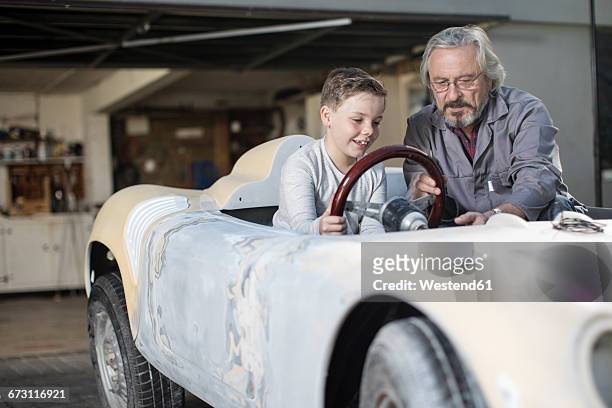senior man explaining convertible to boy - oldtimer stock-fotos und bilder