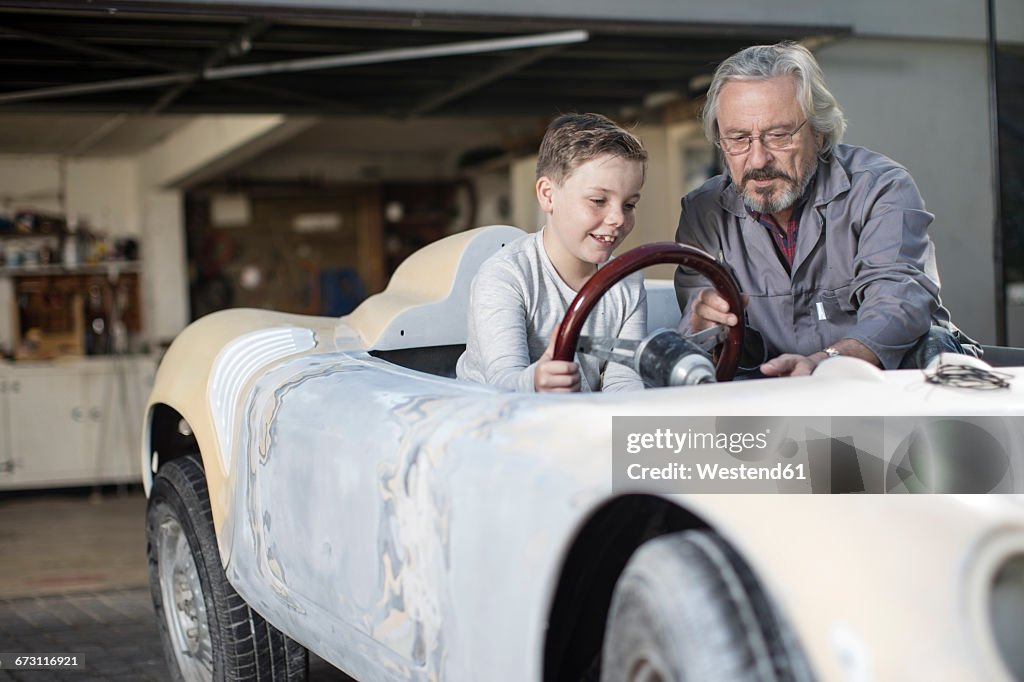 Senior man explaining convertible to boy