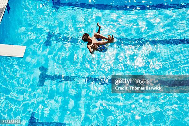 boy doing backflip off diving board into pool - boy in swimwear stock-fotos und bilder