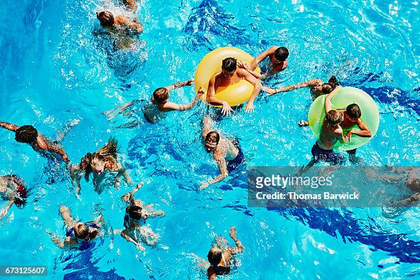 group of kids playing together in outdoor pool - tween girl swimsuit stockfoto's en -beelden
