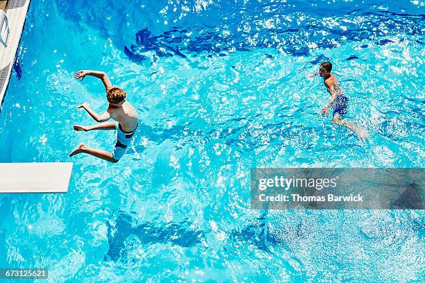 boy jumping off diving board into outdoor pool - freibad stock-fotos und bilder