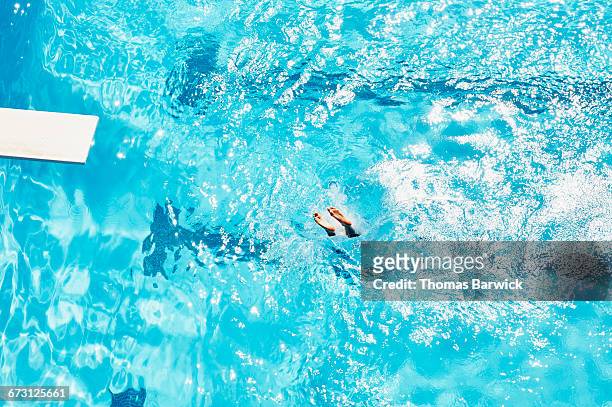 overhead view of splash and feet of boy diving - buitenbad stockfoto's en -beelden