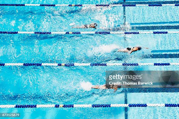 competitive swimmers racing in outdoor pool - rivaliteit stockfoto's en -beelden