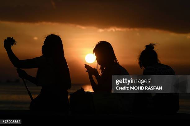 Filipinos take pictures during sunset in Manila on April 26, 2017. Firebrand Philippine President Rodrigo Duterte is set to enjoy much-wanted foreign...