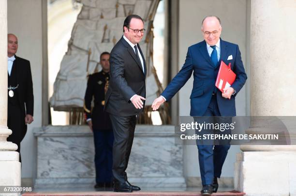 Fench President Francois Hollande shakes hands with French Prime Minister Bernard Cazeneuve as he leaves the weekly cabinet meeting on April 26, 2017...