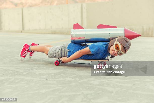 young boy dreams of flying with rocket - skateboard stock pictures, royalty-free photos & images