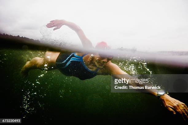 underwater view of mature woman on open water swim - swimming stock-fotos und bilder