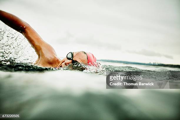 woman taking a breath during open water swim - effort stock pictures, royalty-free photos & images