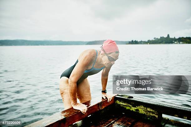 Mature swimmer climbing onto dock after swim