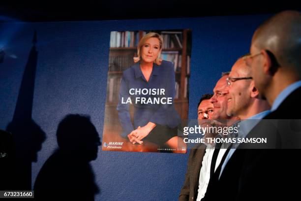 Men stand next to the French far-right party Front National 's official campaign poster and slogan for the second round of the election during a...