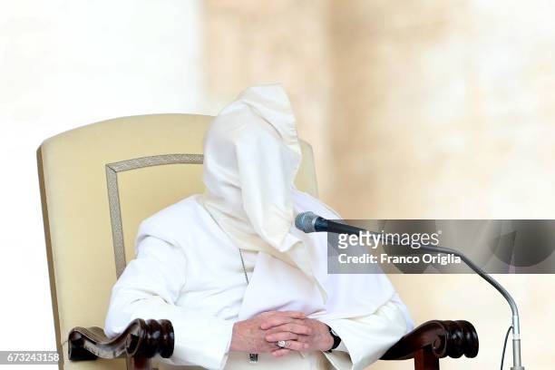 The robes of Pope Francis are blown over his head by a gust of wind as he holds his homily during the weekly audience in St. Peter's Square on April...