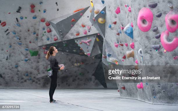 young woman looking up at a climbing wall - herausforderung stock-fotos und bilder