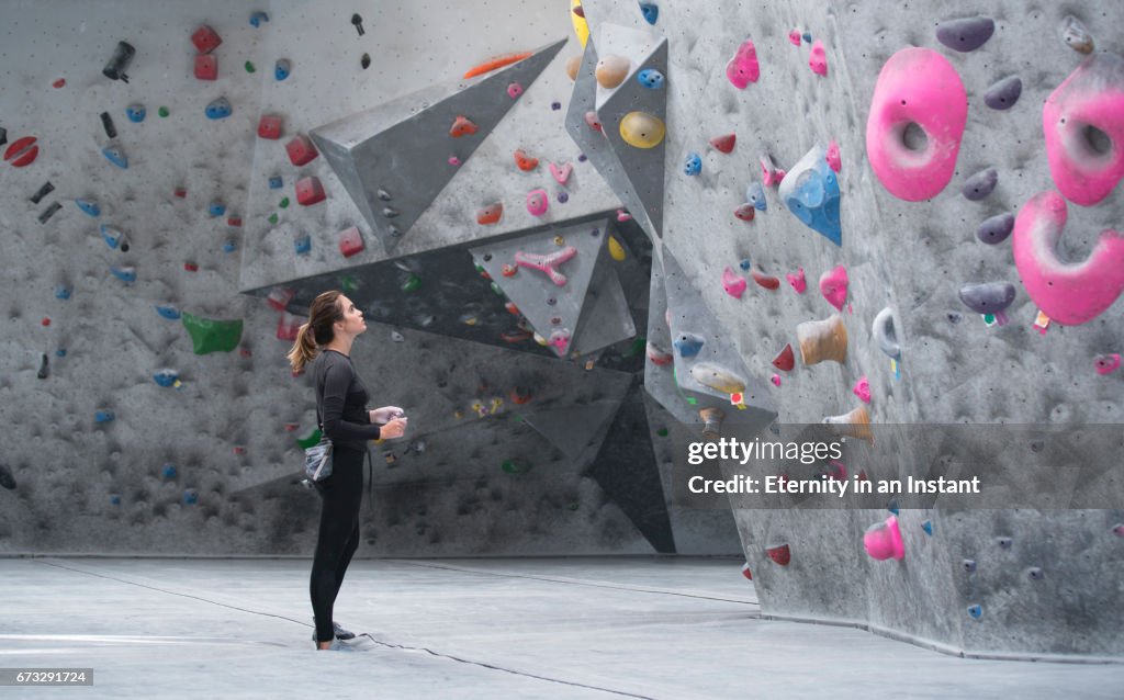 Young woman looking up at a climbing wall