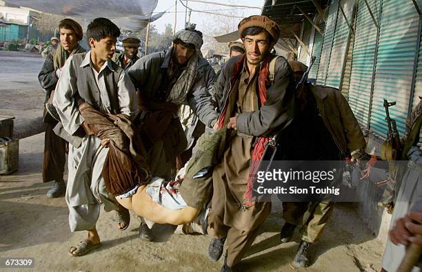 Kunduz residents and Northern Alliance soldiers attempt to drag away a fatally wounded Northern Alliance soldier during street battles between...