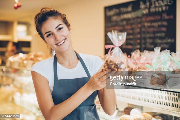 schöne baker, die holding einer cookies-pakets - temptation stock-fotos und bilder