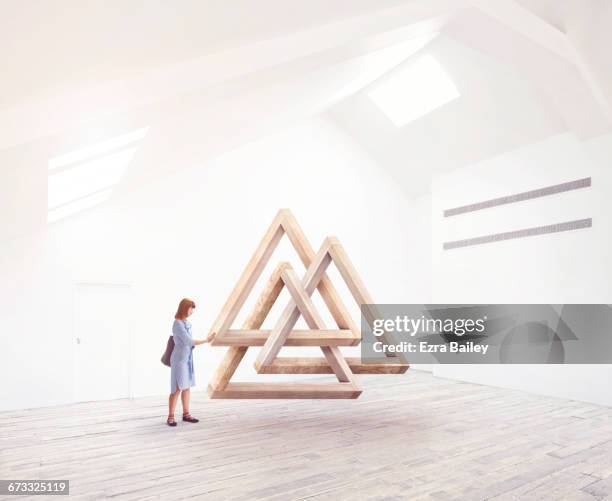 woman being inspired by an impossible triangle. - interlocking shape stock pictures, royalty-free photos & images