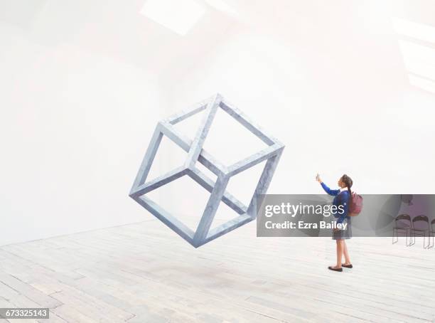 school girl taking a photo of an impossible cube. - mobile sculpture fotografías e imágenes de stock