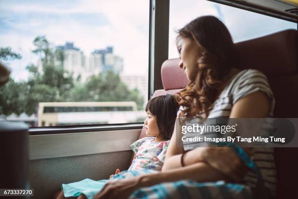 pretty young mom riding a bus with her lovely little daughter joyfully - bus window stock pictures, royalty-free photos & images