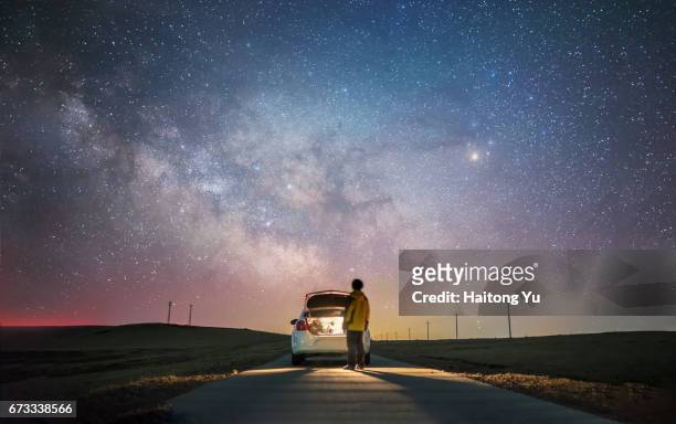 rear view of one man glaring at the palette of milky way with car trunk open - polish car stock-fotos und bilder