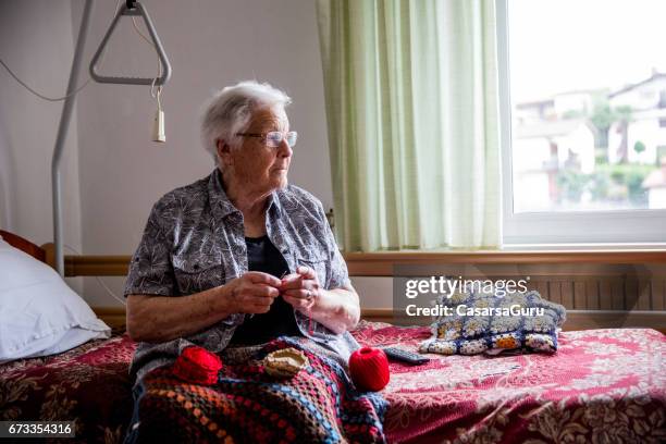senior lady crocheting in her room in retire community - care home bed stock pictures, royalty-free photos & images