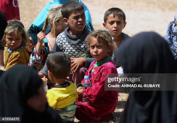 Displaced Iraqi women and children rest during their evacuation from the modern town of Hatra and neighbouring villages, near the eponymous...