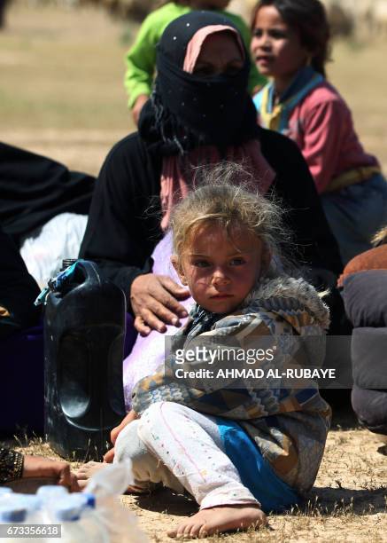 Displaced Iraqi women and children rest during their evacuation from the modern town of Hatra and neighbouring villages, near the eponymous...