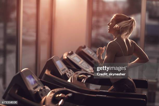 young woman jogging on a treadmill in a gym. - running on treadmill stock pictures, royalty-free photos & images