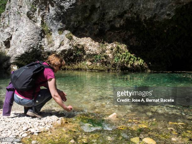 woman tripper in the nature bent together with a river refreshing itself the face and drinking natural water - female looking away from camera serious thinking outside natural stock pictures, royalty-free photos & images