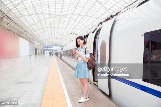 frau wartet auf bahn bahnsteig mit smartphone - high speed train stock-fotos und bilder