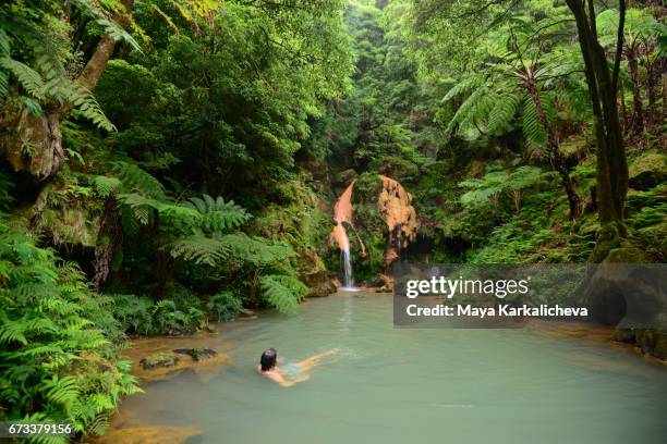 man taking a bath in a hot waterfall, caldeira velha hot springs, azores island - ponta delgada azores portugal stock-fotos und bilder