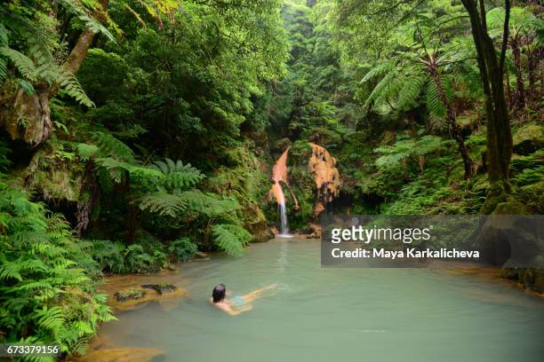 man taking a bath in a hot waterfall, caldeira velha hot springs, azores island - san miguel portugal stockfoto's en -beelden